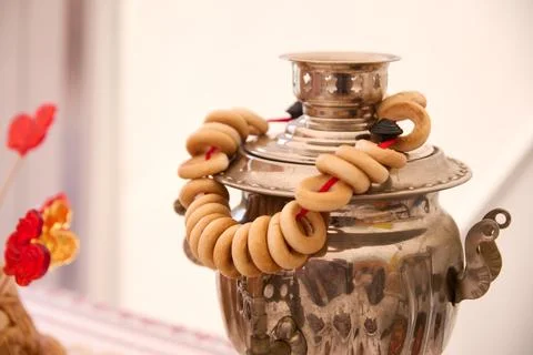 Silver samovar displays bread rings and rooster lollipops in warm light Stock Photos