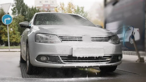 A silver sedan is covered in thick white foam as it undergoes a high-pressure Video stock 304511780