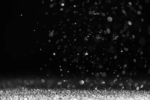 Silver sequins fall on a black background Stock Photos