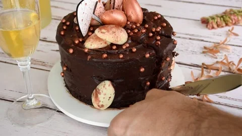 Silver spatula cutting and removing a slice of Easter chocolate cake with icing Stock Footage 158945036