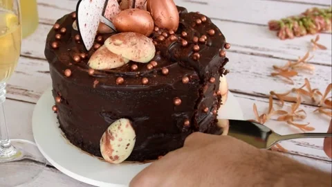 Silver spatula cutting and removing a slice of Easter chocolate cake with icing Stock Footage 158945048