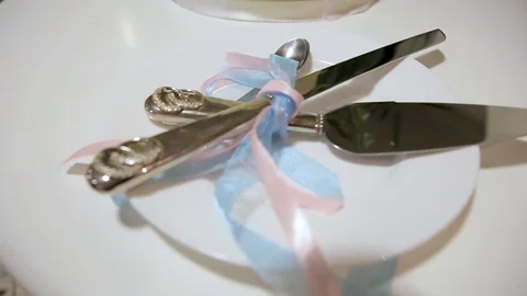 Silver spatula, knife and teaspoons wrapped in blue and pink ribbon on a plate. Stock Footage 129492866