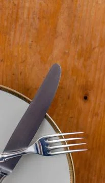 Silver Spoon Fork and Knife Tied on White Dish  wooden table Stock Photos