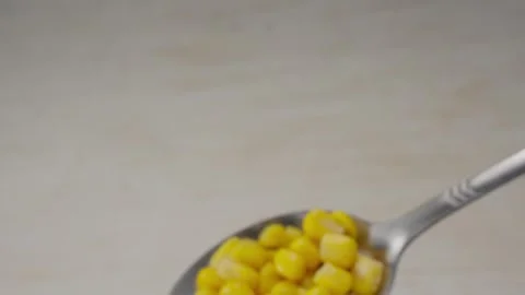 Silver spoon holding bright yellow sweet corn kernels on a white background. Stock Footage 287379149