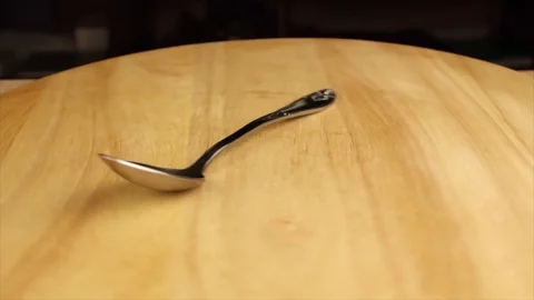 Silver spoon rotates 360 degrees on wooden stand Stock Footage 119235616