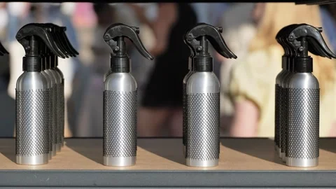 Silver spray bottles with black mesh packaging standing in a row on a shelf Stock Footage 344697981
