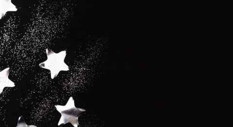 Silver stars and sparkles on black background. Flat lay, copy space. Stock Photos