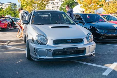 Silver Subaru with modifications, parked in a parking lot amidst other cars C 스톡 사진