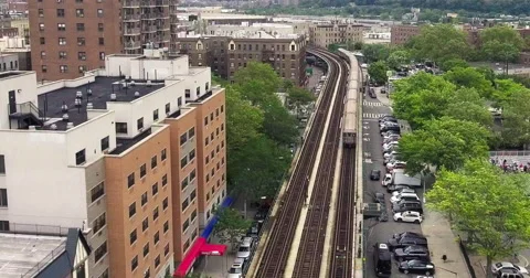 Silver subway train on an elevated line beside Inwood apartment houses Vidéo 65364835