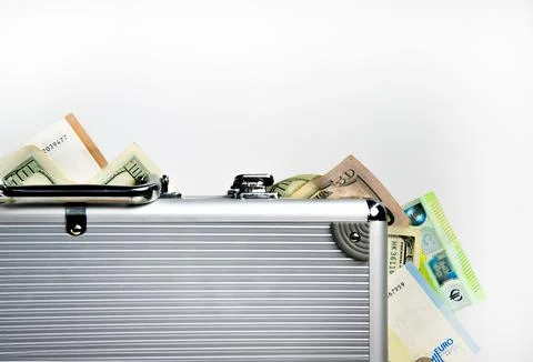 A silver suitcase with a slightly open lid, revealing several dollar bills .. Stock Photos