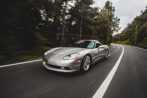 Silver supercar speed performance on the forest road in the evening Stock Photos