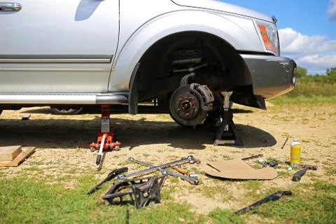 Silver SUV on Tire Jack having Wheel Replaced at Home Stock Photos