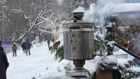 A silver tea kettle sits on a snowy sidewalk in front of a pile of wood Stock Footage 326061948