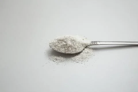 Silver tea spoon full of raw salt on gray background Stock Photos