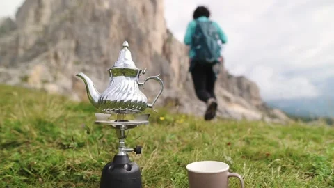 Silver teapot and two cups in grass with rocky Dolomite wall in background Stock Footage 318514564