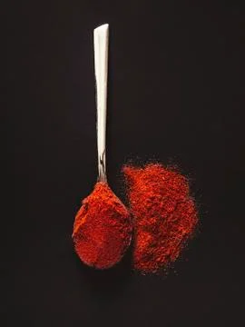 Silver teaspoon with hot red chilli pepper on a black background. Stock Photos