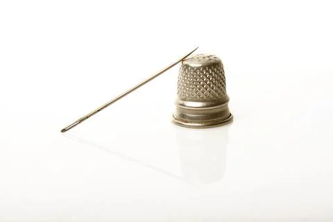 Silver thimble and needle over white background Stock Photos