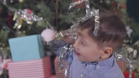 Silver tinsel pours down on the boy's face. Close-up. Stock-Footage 144378635