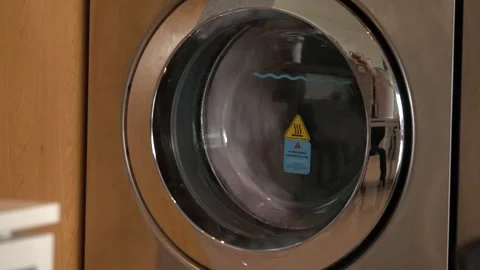 A silver washing machine with a yellow label on the door Stock Footage 296397191