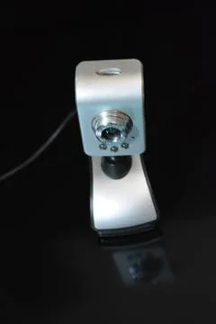 Silver web camera of computer with wires and reflection on black background Stock Photos