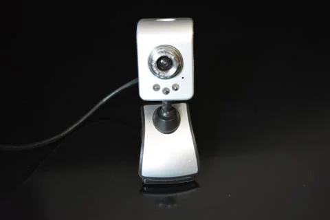 Silver web camera of computer with wires and reflection on black background 写真素材