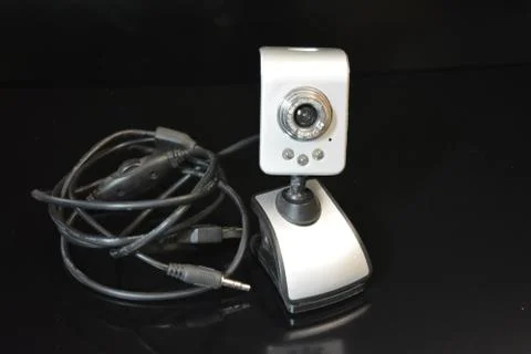 Silver web camera of computer with wires and reflection on black background Foto stock