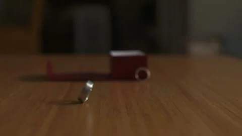 Silver wedding ring spins in slow motion on top of wooden table. Stock Footage 135236888