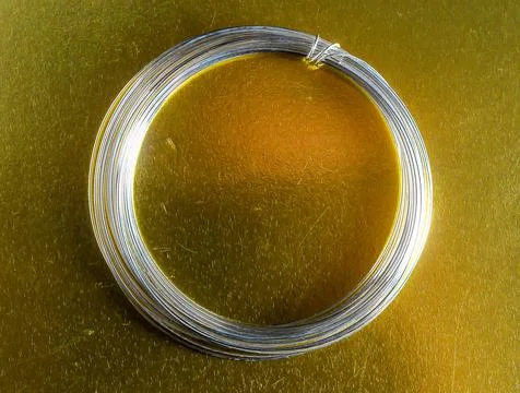 A silver wire is wrapped around a gold surface Stock Photos