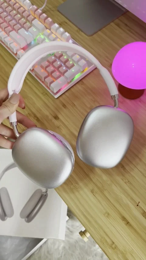 Silver wireless headphones held above a pink aesthetic desk 스톡 동영상 331771096