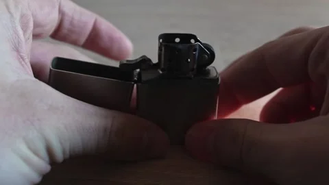 Silver zippo on an interior table being flicked open and ignited after Stock Footage 175316014