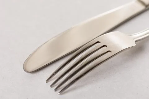Silverware metal fork and knife on the white marble background with copy spac Stock Photos