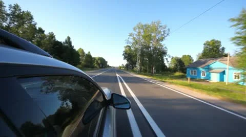 Silvery car goes on asphalted highway through village Stock Footage