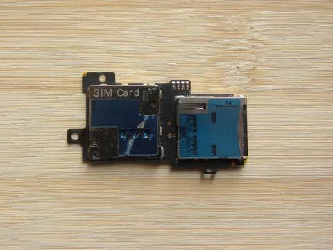 SIM card and memory card slot module of smartphone kept on wooden table Stock Photos