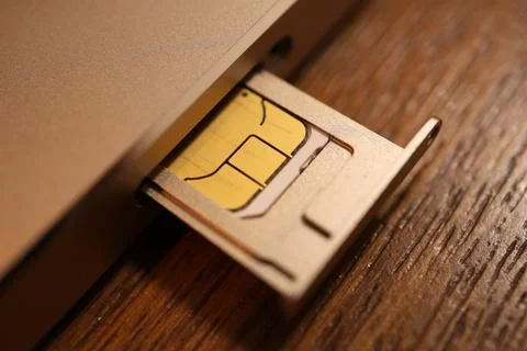 SIM card and nano-SIM tray ejecting from a mobile smartphone device resting.. Stock Photos