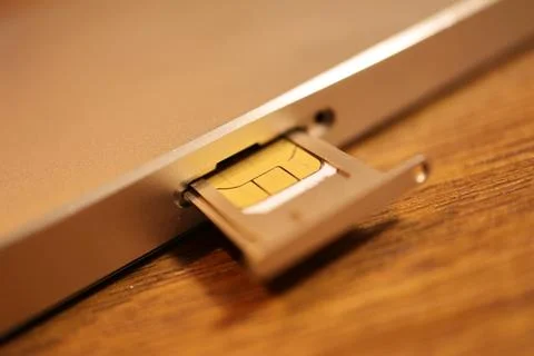 SIM card on ejection tray being inserted into a mobile smartphone device on.. Stock Photos