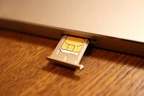 SIM card on ejection tray being inserted into a mobile smartphone device on.. Stock Photos