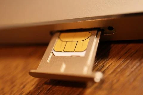 SIM card inserted in a metal tray being ejected from a tablet or smartphone.. Stock Photos