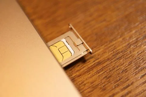 SIM card inserted into a mobile phone card tray showing the gold electronic.. Stock Photos