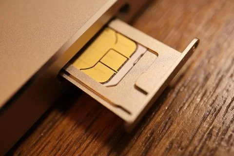SIM card inserted in a smartphone tray slider on a gold mobile phone device.. Stock Photos