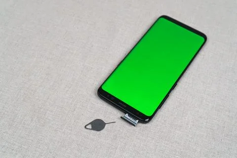 Sim card tray and smartphone with green screen and eject tool Stock Photos