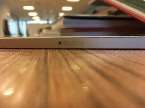 The sim card tray of an apple iphone in an office environment. Pinhole visible Stock Photos