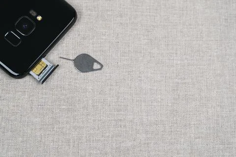 Sim card tray of smartphone and eject tool on fabric background Stock Photos