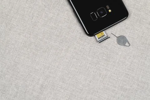 Sim ejector tool and SIM card slot of mobile phone. Top view Stock Photos