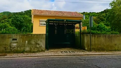 A simple and empty Colares bus stop on the sidewalk with house and trees in the Stock Photos