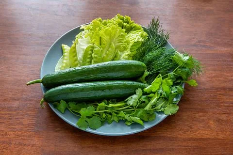 A simple appetizer with fresh cucumbers, lettuce, dill, cilantro and green pe Stock Photos