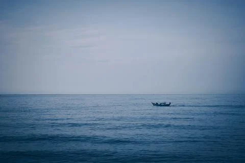 Simple background Calm dark blue sea fishing boat alone white pale Spindrift Stock Photos