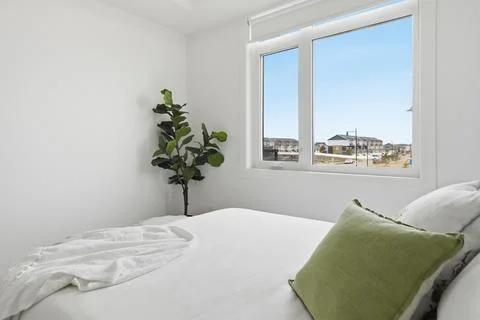 Simple bedroom interior with window view, green pillow, and plant Stock Photos