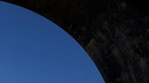 Simple blue sky background with copy space with dark weathered arch of bridge Stock Photos