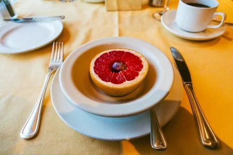 A simple breakfast plate featuring a halved grapefruit topped with a single.. Stock Photos