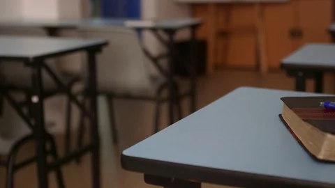 A simple brown leather bible with a blue pen on a blue student desk Stock Footage 76879244